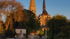 A historic church with twin spires, a reflection in the water, and a bridge in the foreground. - City center studio (Vendôme)