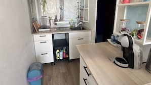 A compact kitchen with a built-in stove, a sink, and a countertop with a coffee machine. There are cabinets and a small trash bin. - City center studio (Vendôme)