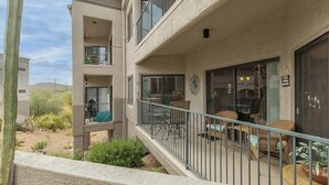 Un immeuble résidentiel à plusieurs étages, doté de balcons, d’un espace extérieur aménagé et surplombant un paysage désertique.