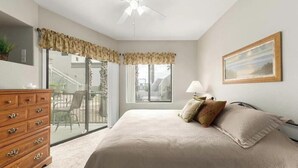 Une chambre à coucher avec un lit, une commode, une fenêtre et un ventilateur de plafond.