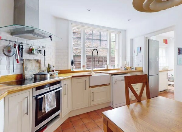 A kitchen with white cabinets, a stove, a sink, and a window. - Stunning period property. 15 min train central London/Gatwick. (Croydon)