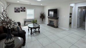 Uma sala de estar ampla com lareira, televisão e mesa de centro.