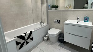 Moderni kylpyhuone, jossa on kylpyamme, wc ja pesuallas.