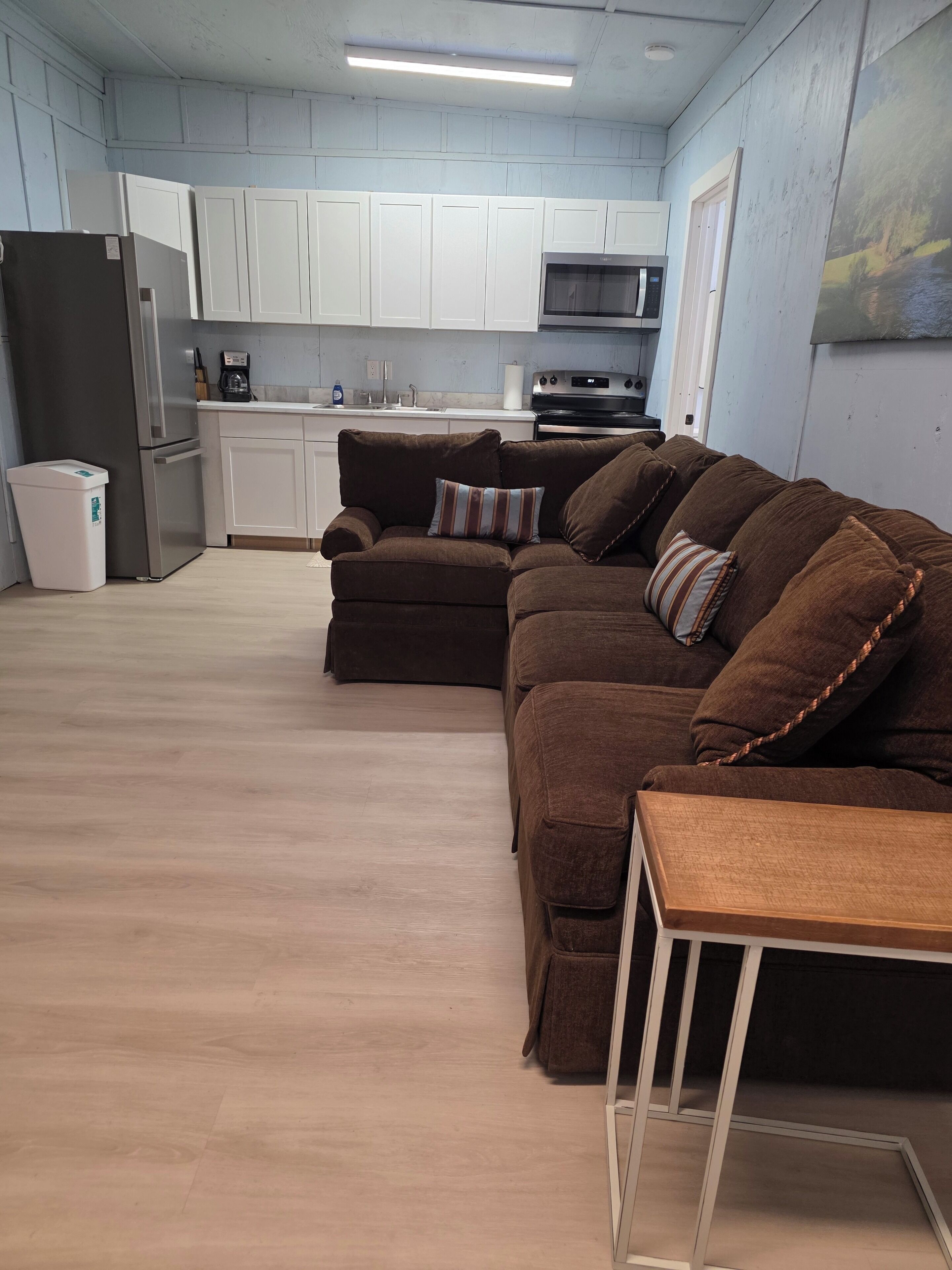 A modern kitchen with white cabinets, a stainless steel refrigerator, and a microwave.