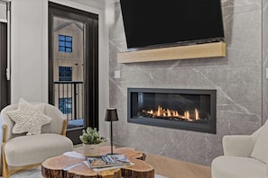 A modern living room with a fireplace, a mounted TV, and a comfortable seating area. - Ascent Luxe Retreat | Brand-New 2BR (Canmore)