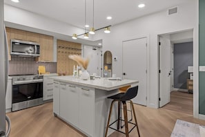 A modern kitchen with a central island, stainless steel appliances, and pendant lighting. - Ascent Luxe Retreat | Brand-New 2BR (Canmore)