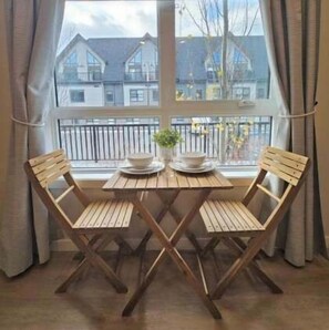 A wooden table with two chairs in front of a window with a view of buildings. - Skyline Peaks Mountain Retreat - Studio (Canmore)