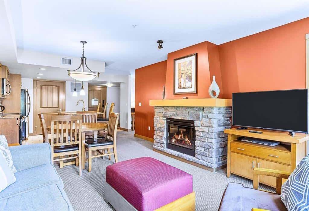 A living room with a fireplace, a television, and a dining area.