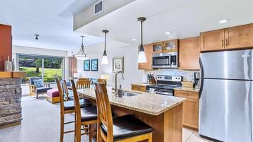 A modern kitchen with granite countertops, stainless steel appliances, wooden cabinets, and a dining area with a large island.