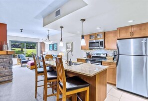 Una cocina moderna con encimeras de granito, electrodomésticos de acero inoxidable, armarios de madera y un comedor con una isla grande.