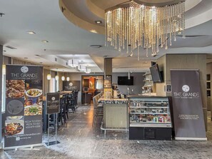 A restaurant interior with a bar area, a chandelier, and a counter displaying food items. - Rockies' Embrace- Pool, HotTub, Gym, BBQ, Parking (Canmore)