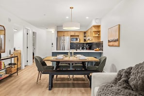 A modern kitchen with wooden cabinets, a built-in microwave, and a stainless steel refrigerator. - Magpie Lookout - Newly Renovated Mountain Escape (Canmore)