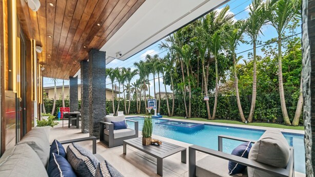 A modern outdoor living area with a pool, outdoor furniture, and a view of a tropical landscape. - Luxury Villa w/ Heated Pool / Jacuzzi / 6BR /Games/ Miami (Miami)