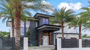 A modern two-story house with a flat roof, large windows, and a gated entrance. - Luxury Villa w/ Heated Pool / Jacuzzi / 6BR /Games/ Miami (Miami)