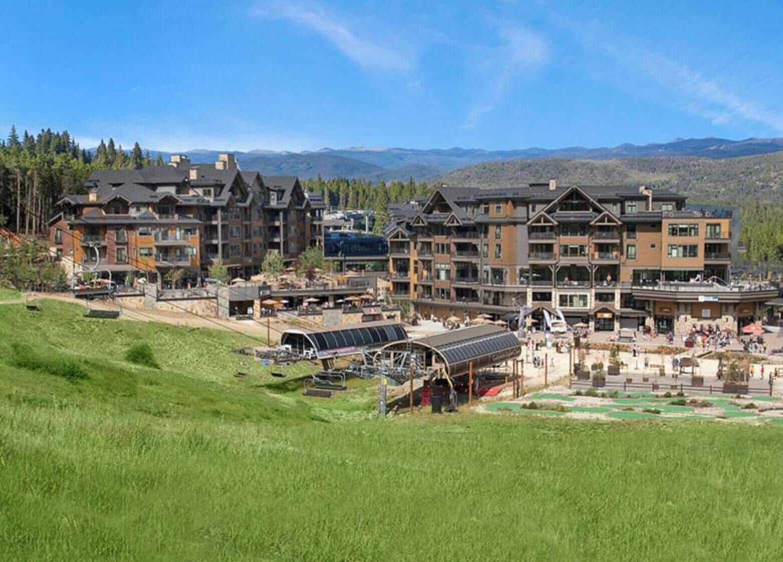 A multi-story hotel with a ski lift and a ski resort in the background.