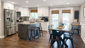 A modern kitchen with a central island, stainless steel appliances, and a dining area with a wooden table and chairs. - Groups Welcome-Sleeps 20-Pets OK-Fire Pit-BBQ (Charlotte)