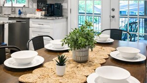 A modern kitchen with white cabinets, a coffee machine, and a dining area with a table set for four. - Groups Welcome-Sleeps 20-Pets OK-Fire Pit-BBQ (Charlotte)
