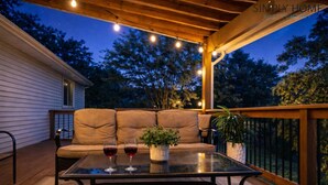 An outdoor patio with a sofa, two wine glasses, and a potted plant. - Groups Welcome-Sleeps 20-Pets OK-Fire Pit-BBQ (Charlotte)