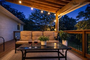 Eine Terrasse im Freien mit einer Couch, zwei Weingläsern und einem Blumentopf.