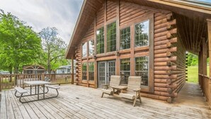 A log cabin with a deck, large windows, and outdoor seating. - Water's Edge RV Resort (Willis)