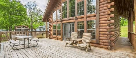 A log cabin with a deck, large windows, and outdoor seating.
