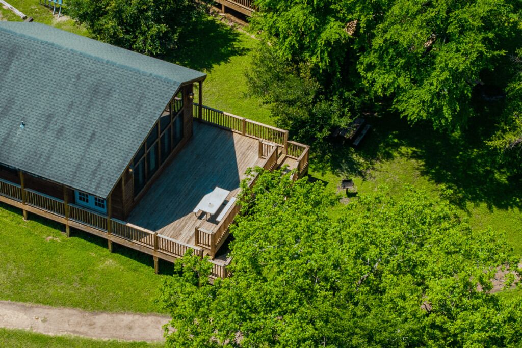 Eine Lodge mit einer großen Terrasse, umgeben von dichtem Grün.