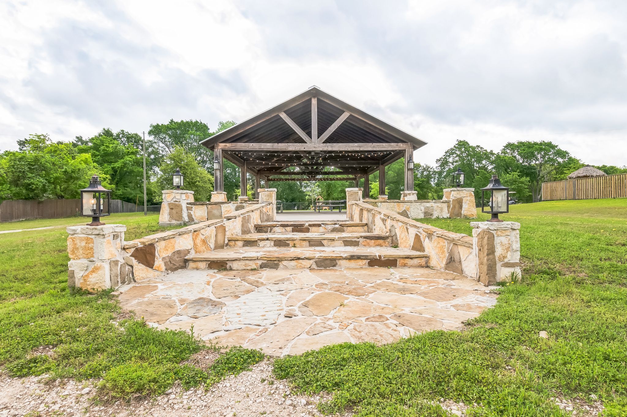 A gazebo with stone steps leading up to it, surrounded by a grassy area.