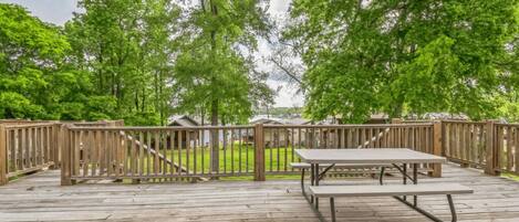 A wooden deck with a picnic table, surrounded by wooden fences and trees.
