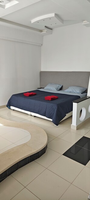 A modern bedroom with a bed, a round seating area, and a white console table. - Dar Essaada - Exceptional duplex, 2 minutes from the beach (Hiboun)