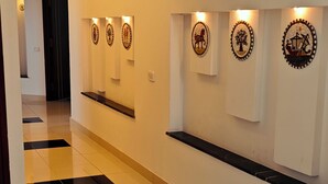 A hallway with a tiled floor, recessed lighting, and wall-mounted artwork.