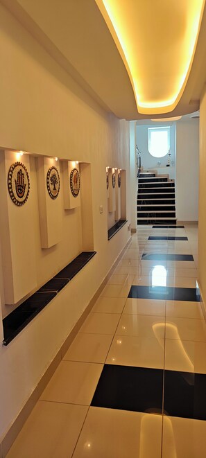 A modern hallway with a tiled floor, a staircase, and wall-mounted artwork.