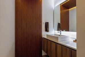 Ein modernes Badezimmer mit einer Wand aus Holzpaneelen, einem weißen Waschbecken und einem großen Spiegel.