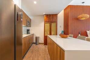 Eine moderne Küche mit Holzausstattung, einem Edelstahlkühlschrank und einer weißen Arbeitsplatte.