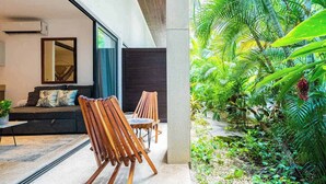 Un interno moderno con un divano, sedie in legno e un'ampia finestra che si affaccia su un rigoglioso giardino.