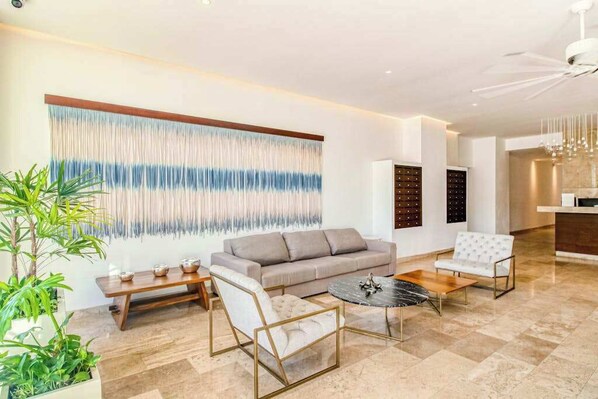 A modern living room with a sofa, two armchairs, a coffee table, and a large abstract wall art piece.
