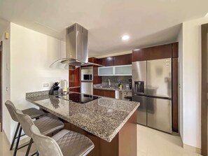 Una cocina moderna con una isla central, electrodomésticos de acero inoxidable y un microondas integrado.