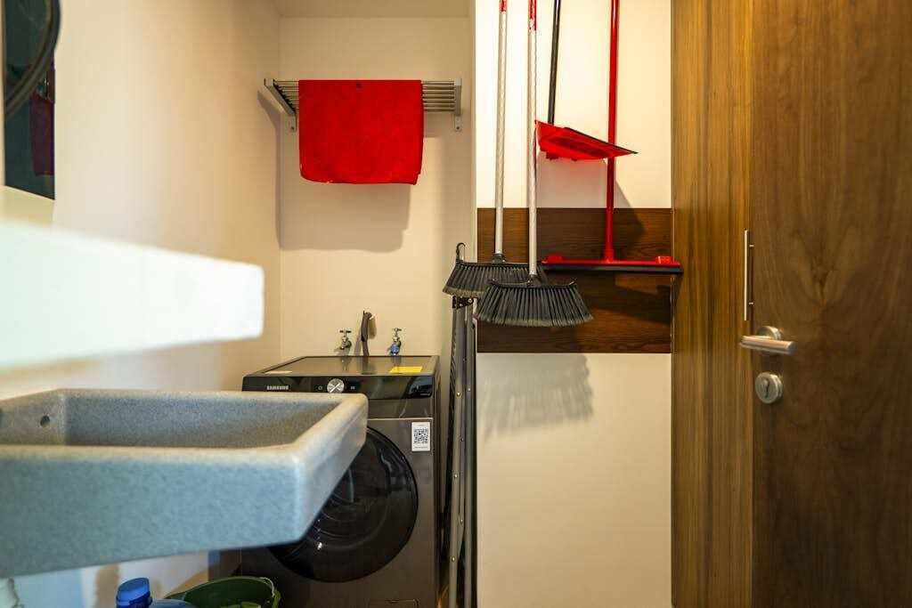 Zona de lavandería con lavadora, lavabo y una toalla roja colgada en un tendedero.
