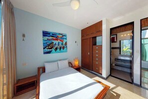 Ein Schlafzimmer mit einem Bett, einem Gemälde, einem Kleiderschrank und einem durch eine offene Tür einsehbaren Badezimmer.