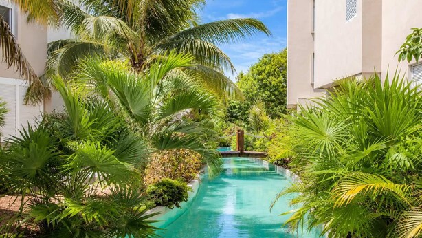 Ein Pool, umgeben von üppiger Vegetation und Gebäuden.