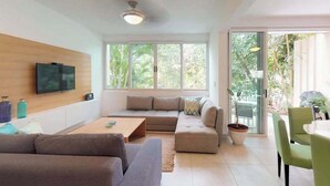 Ein modernes Wohnzimmer mit einer Couch, einem Couchtisch und einem an der Wand montierten Fernseher.