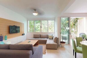 A modern living room with a sofa, a coffee table, and a TV mounted on the wall. - Playa del Carmen 3BR Villa | Pool, Gym & Balcony (Playa del Carmen)