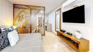 A modern bedroom with a bed, a TV, a wooden console, and an air conditioning unit. - Perfect Place 211 | Studio, Rooftop Pool & Gym (Playa del Carmen)