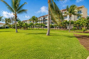 A hotel with a well-maintained lawn, palm trees, and a multi-story building with balconies. - Playa Condo: Beach, Pool, & Family Fun! (Playa del Carmen)
