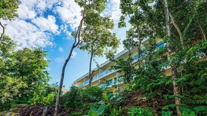 Un hotel con diversi piani, immerso nel verde e circondato da alberi.