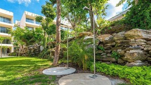 Un giardino curato con un muro in pietra, alberi e un edificio sullo sfondo.
