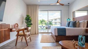 A hotel room with a bed, a desk, a chair, a TV, a ceiling fan, a large window, and a balcony. - Playacar Studio | 4 Pools, Gym, AC & WiFi (Playa del Carmen)