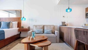A compact hotel room with a bed, a sofa, a small table, and a kitchenette. - Playacar Studio | 4 Pools, Gym, AC & WiFi (Playa del Carmen)