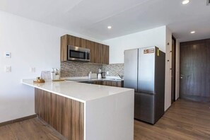 A modern kitchen with a central island, stainless steel appliances, and wooden cabinetry. - Playacar Accessible Condo - Pools - Sleeps 7 (Playa del Carmen)