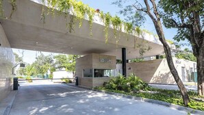 Un edificio moderno con facciata in cemento, un ingresso ben visibile e vegetazione circostante.