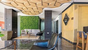 A modern lobby with a green wall, a reception desk, a sofa, and a black leather chair. - Studio | Rooftop Pool & Gym, Steps to Beach (Playa del Carmen)